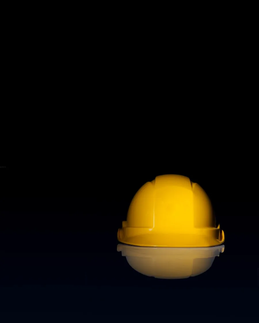 Casco de seguridad amarillo con reflejo sobre fondo oscuro