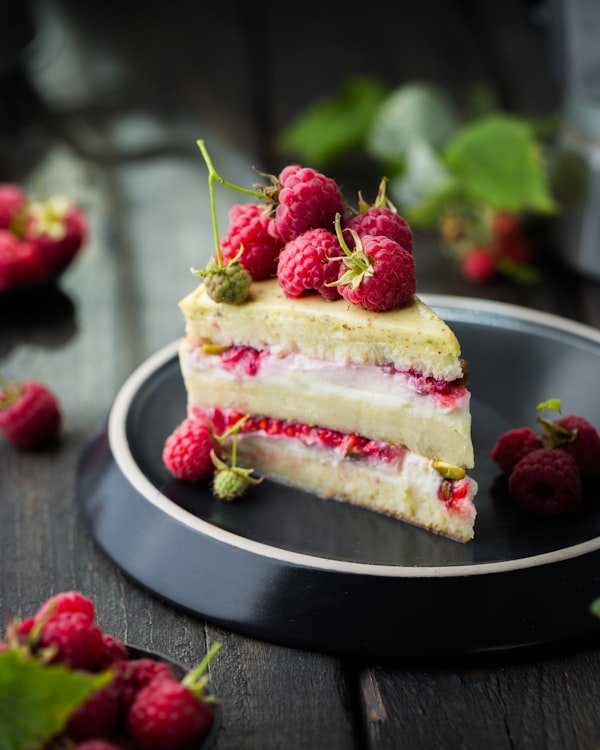 Porción de torta de frambuesa con crema y frambuesas frescas por arriba