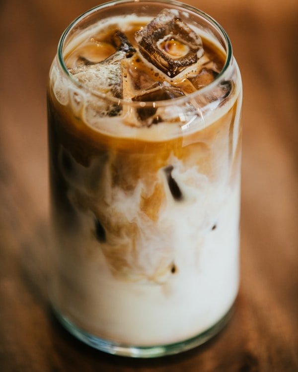 Iced latte en vaso de vidrio, con hielo y la leche cayendo sobre el café