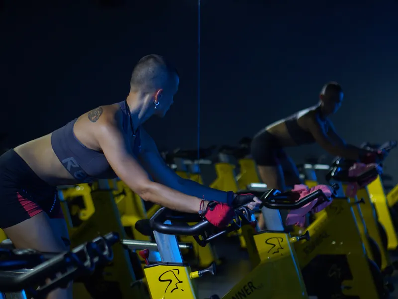 Sala de bicicletas fijas con luz de colores durante una clase de spinning