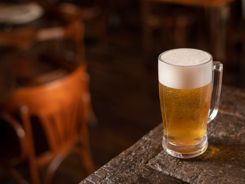 Chop de cerveza tirada con espuma sobre mesa de madera