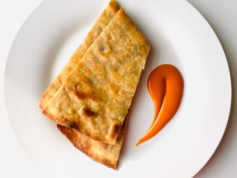 Porción de fainá de garbanzo dorada en plato blanco