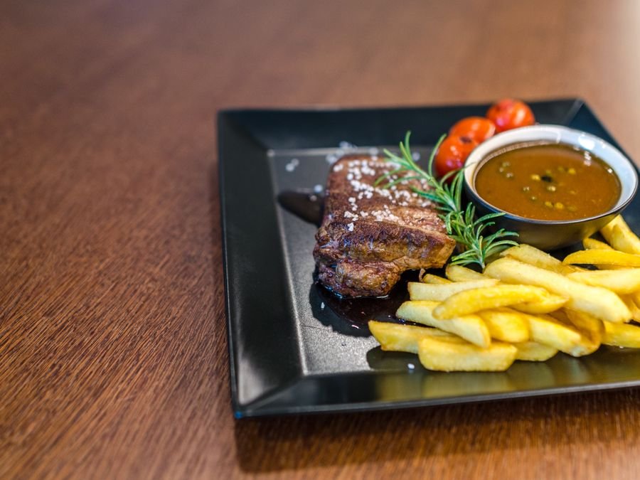 Plato de carne con papas fritas y tomates cherry