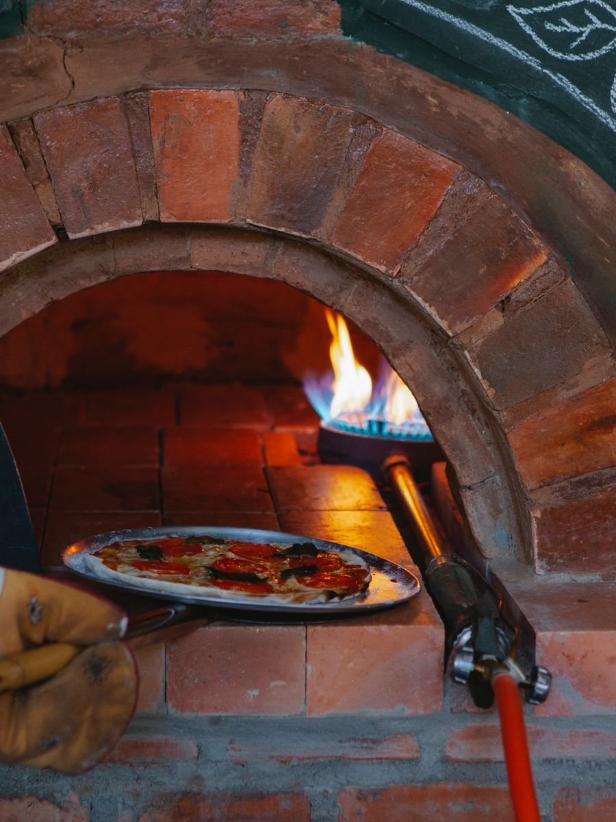 Pizzero colocando una pizza dentro del horno a leña
