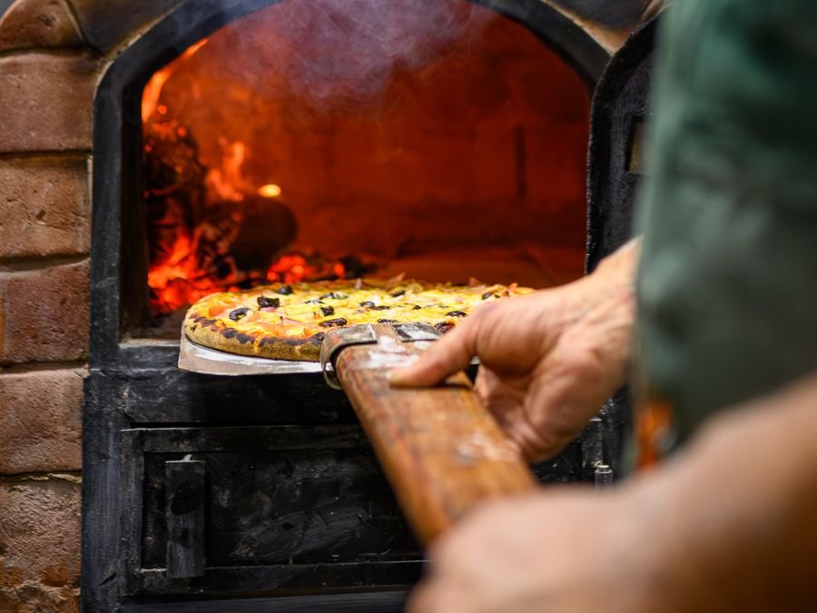 Pizza artesanal horneándose sobre la piedra del horno