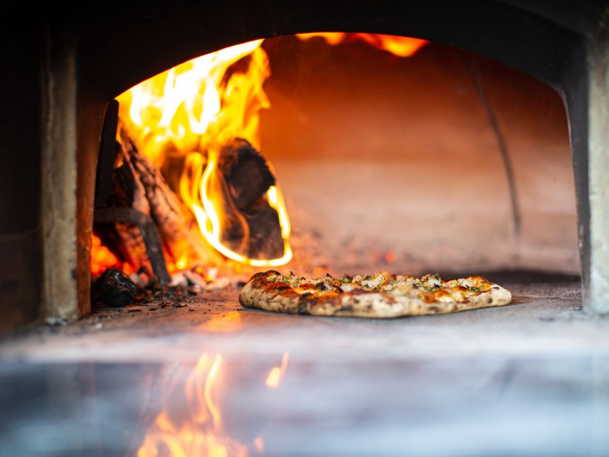 Pizza dentro del horno a leña encendido de La Cuadra